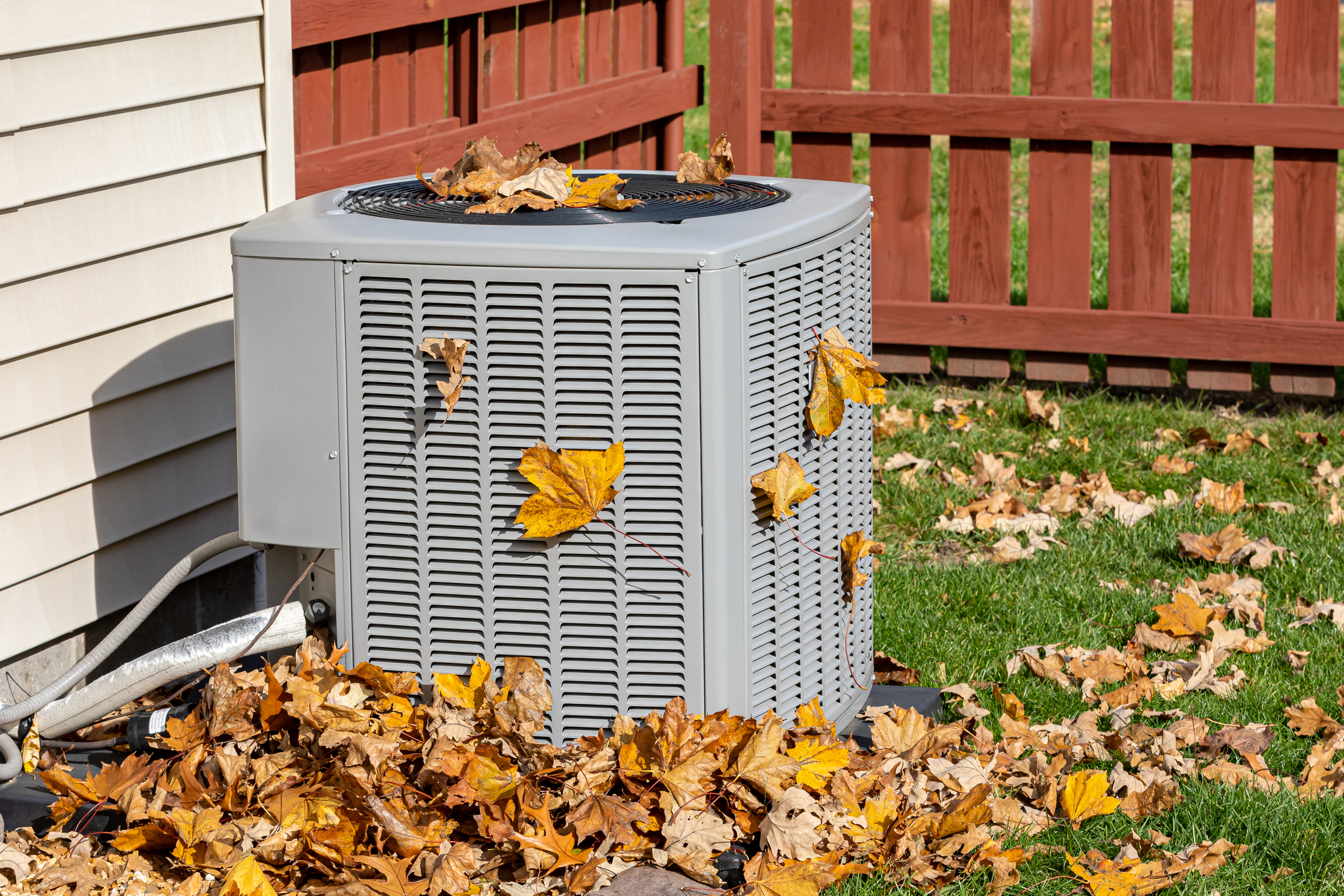 HVAC unit outdoors surrounded by fallen leaves