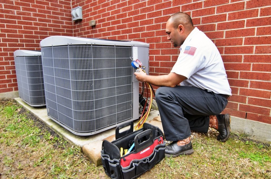 HVAC technician tuning up an outdoor AC unit