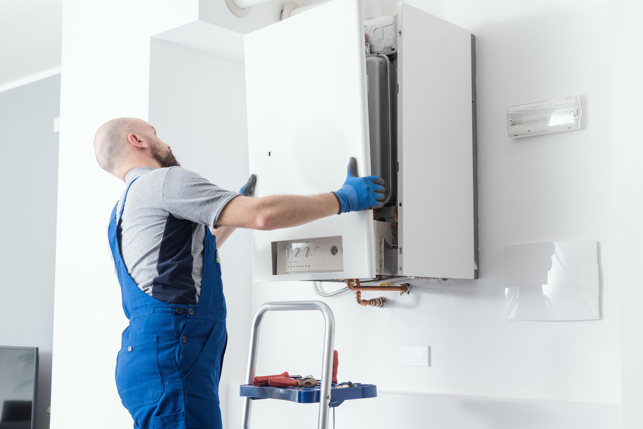 HVAC tech replacing the front panel of a boiler after replacing the unit