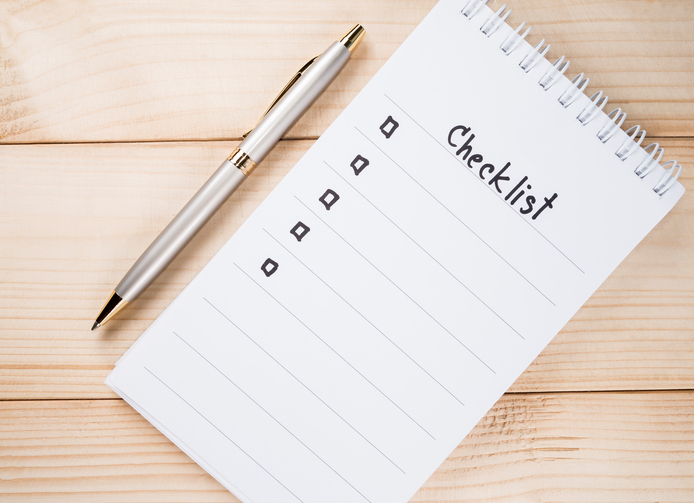 Checklist on a table with a pen next to it